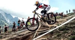 Ciclista descendo trilha íngreme de mountain bike com público ao redor