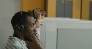 Atendente com fone de ouvido diante de computador em central de atendimento