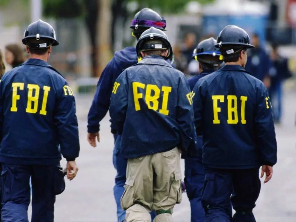 Agentes de costas com jaquetas escuras e a sigla 'FBI' estampada