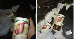 Montagem noturna com mão segurando garrafa de bebida e garrafas caídas no chão