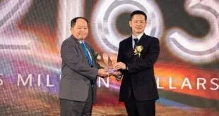 Dois homens de terno apertando as mãos e segurando troféu em cerimônia de premiação