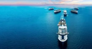 Vista aérea de navio de cruzeiro navegando em mar azul com outras embarcações ao fundo no fim da tarde