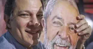 Homem sorrindo em primeiro plano diante de painel com o rosto de outro homem
