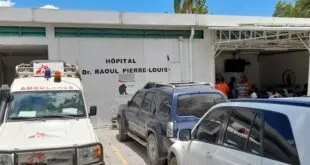 Fachada de hospital com o letreiro 'Hôpital Dr Raoul Pierre Louis' e veículos estacionados na entrada