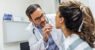 Médico de jaleco branco e estetoscópio conversando com paciente em consultório