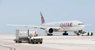 Avião cargueiro da Qatar Airways no pátio do aeroporto ao lado de contêineres de carga
