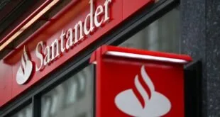 Fachada de agência bancária com letreiro vermelho do Santander e a chama do logotipo em branco