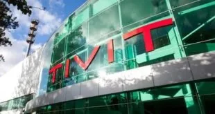 Fachada de prédio corporativo de vidro verde com o letreiro TIVIT em letras vermelhas