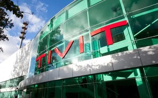 Fachada de prédio corporativo de vidro verde com o letreiro TIVIT em letras vermelhas