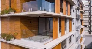 Sacada de prédio residencial com guarda-corpo de vidro e revestimento de madeira na fachada