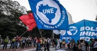 Manifestantes em rua erguendo bandeiras azuis da União Nacional dos Estudantes