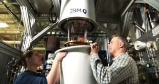 Dois homens manuseiam cilindro metálico de computador quântico com a marca 'IBM Q'
