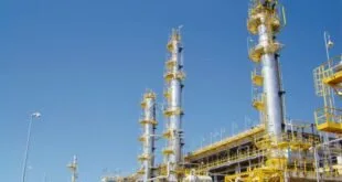 Torres e tubulações amarelas de complexo industrial de refino sob céu azul