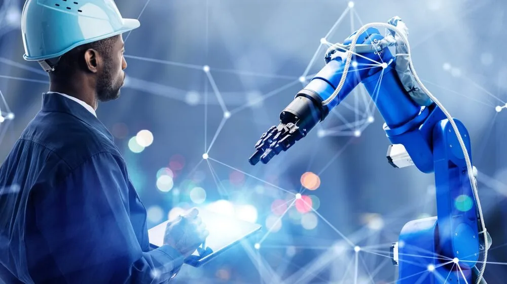 Homem de capacete branco tocando a mão de um braço robótico sobre fundo digital com pontos conectados