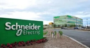 Placa verde com o logotipo da Schneider Electric na entrada de complexo empresarial com jardim