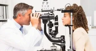 Oftalmologista examinando os olhos de uma paciente em aparelho de consultório, com tabela de letras ao fundo