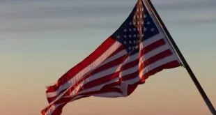 Bandeira dos Estados Unidos hasteada tremulando ao entardecer sob céu alaranjado