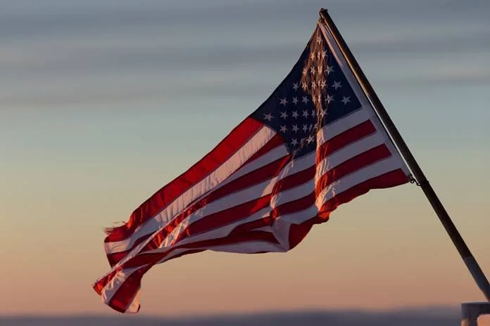Bandeira dos Estados Unidos hasteada tremulando ao entardecer sob céu alaranjado