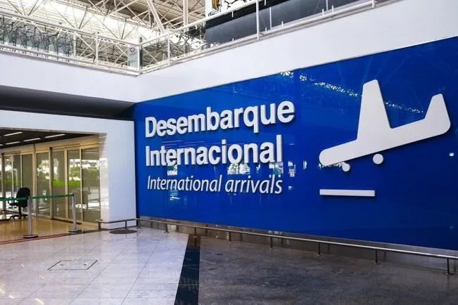 Painel azul com os dizeres 'Desembarque Internacional' em saguão de aeroporto