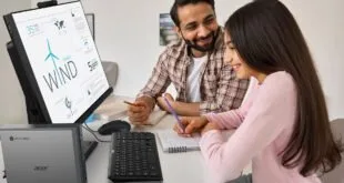 Homem e menina sorriem diante de monitor com infográfico de energia eólica e computador Acer