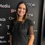 Mulher de vestido preto em pé diante de painel escuro com termos de marketing digital