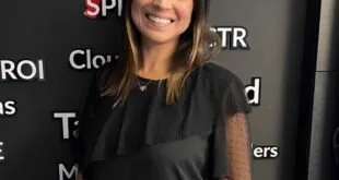 Mulher de vestido preto em pé diante de painel escuro com termos de marketing digital