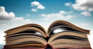 Livros abertos empilhados contra céu azul com nuvens, imagem ilustrativa