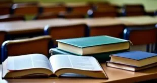 Livros empilhados e caderno aberto sobre carteira em sala de aula vazia