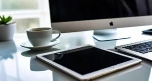 Tablet branco e xícara de café sobre mesa clara ao lado de monitor de computador