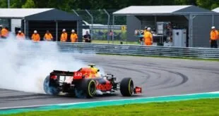 Carro de Fórmula 1 derrapa com fumaça nos pneus em curva de autódromo diante de fiscais