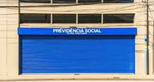 Porta de aço azul fechada com letreiro 'Previdência Social' acima da entrada