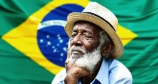 Homem idoso de chapéu de palha com expressão pensativa diante da bandeira do Brasil