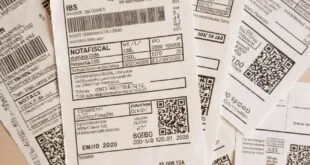 Notas fiscais impressas espalhadas sobre mesa com códigos de barras e QR codes