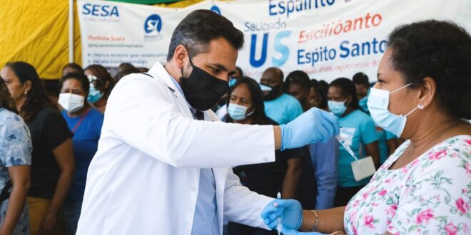 Profissional de saúde em uniforme atendendo paciente em unidade de saúde pública