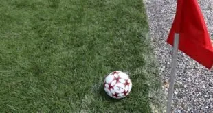 Uma bola de futebol branca e vermelha está posicionada na grama ao lado, ilustração sobre Juventus enfrenta o Parma