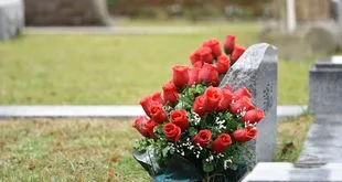Túmulos de cemitério enfeitados com flores e velas em dia de Finados