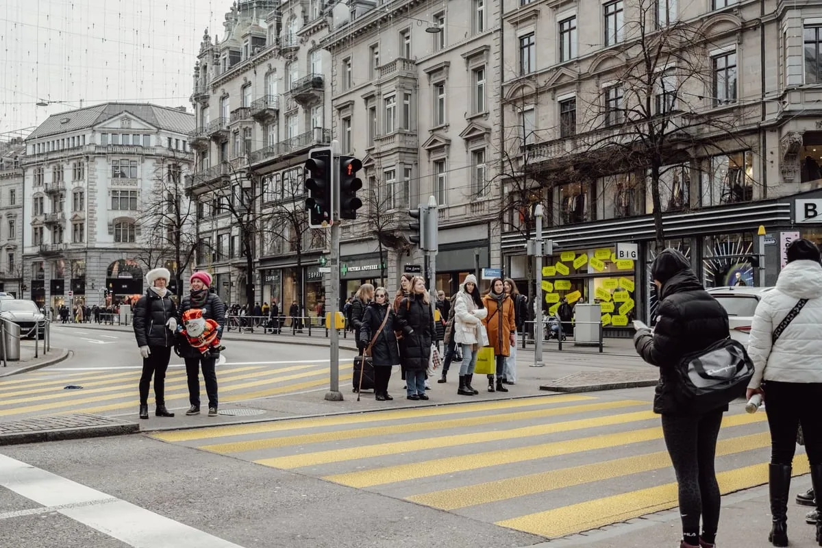 Multidão de pessoas atravessando uma grande avenida em uma cidade movimentada
