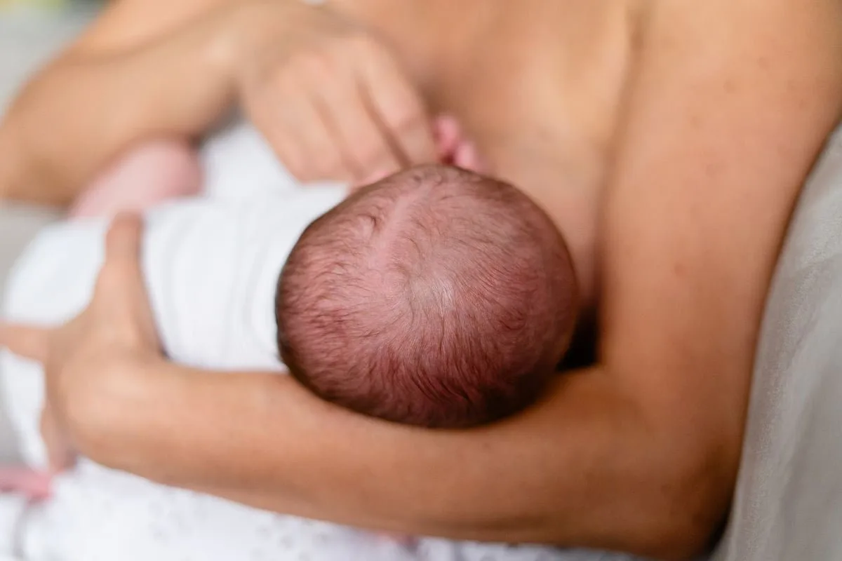 Mãe amamentando bebê recém-nascido em enfermaria de maternidade