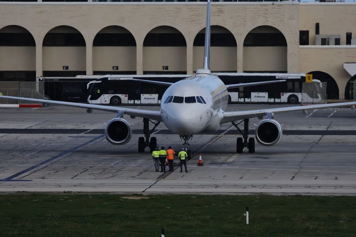 Equipe de rampa carregando bagagens ao lado de avião estacionado no pátio do aeroporto