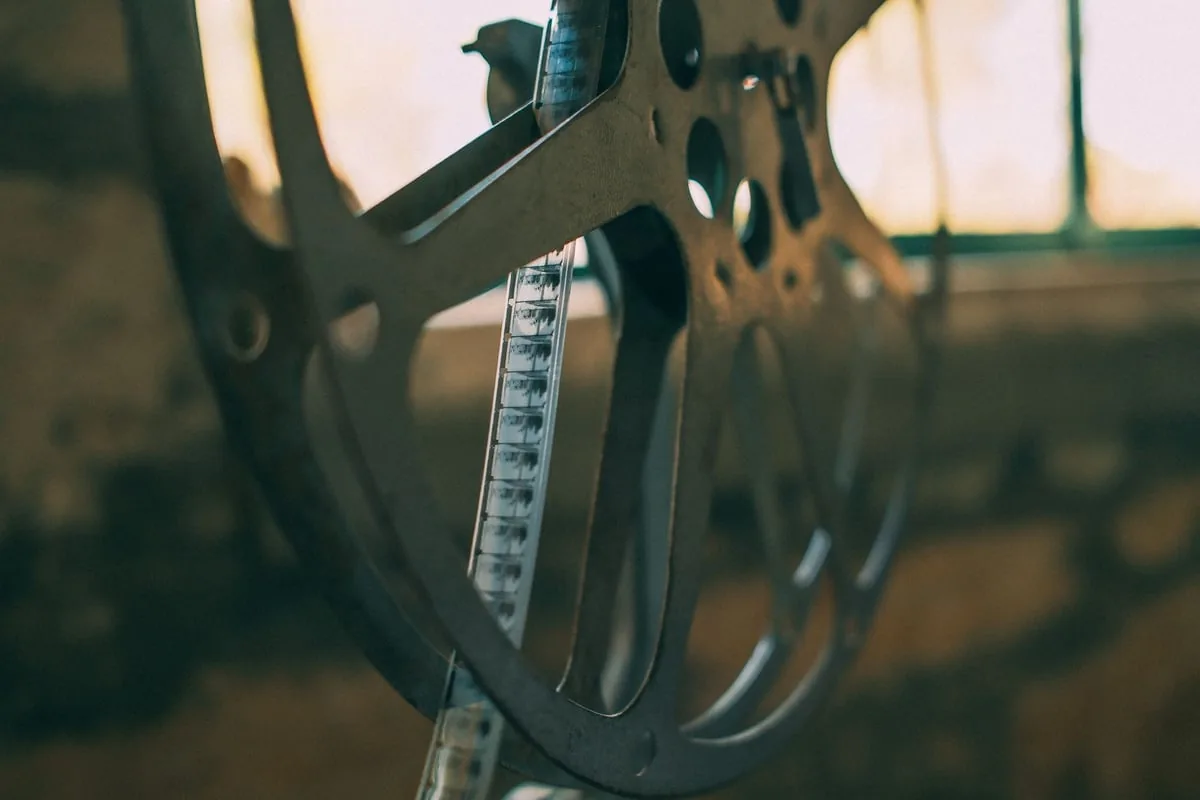 Rolo de filme antigo ao lado de projetor de cinema vintage sobre mesa
