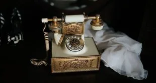 Telefone antigo de linha fixa sobre mesa de madeira no Dia do Telefone