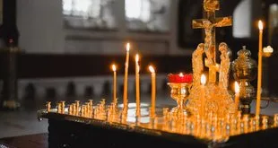 Vela acesa diante de imagem de Nossa Senhora Aparecida em altar de igreja católica, ambiente de devoção