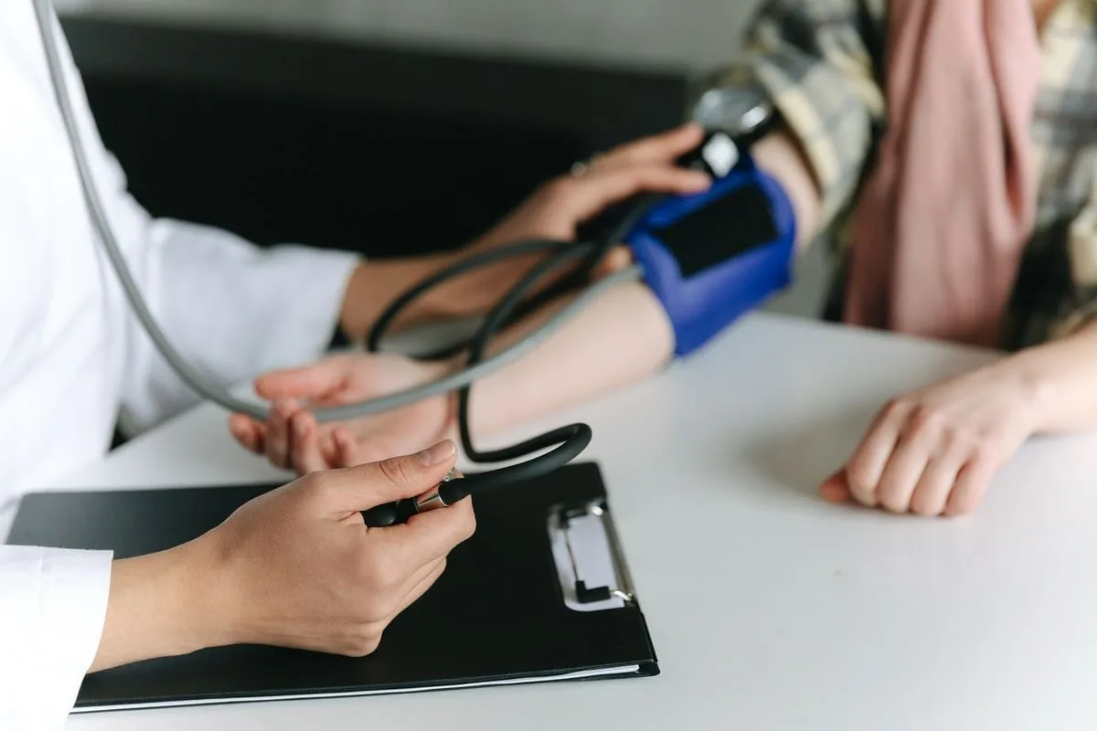Profissional de saúde aferindo pressão arterial de paciente em posto de saúde