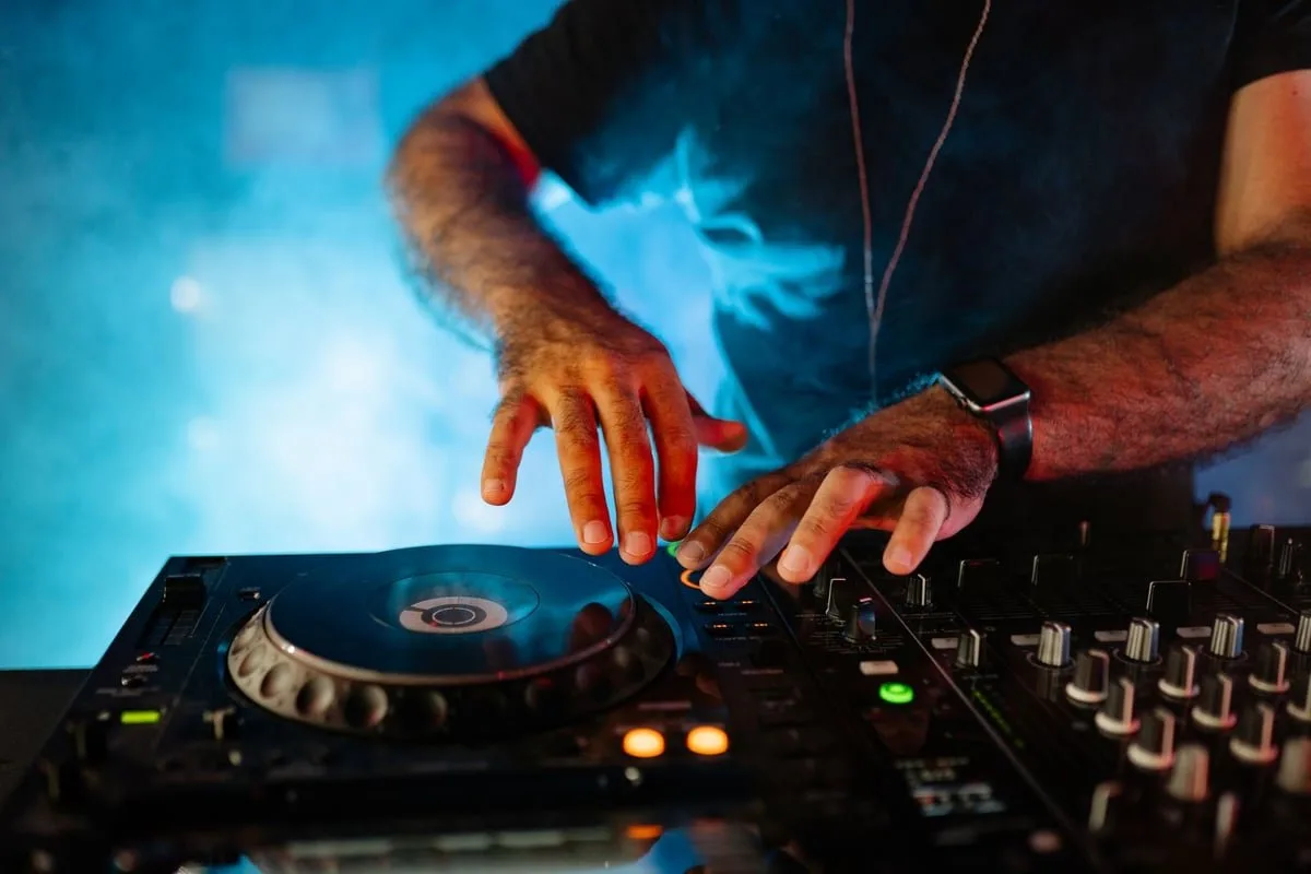 DJ manuseia mesa de som e toca-discos em cabine durante festa noturna