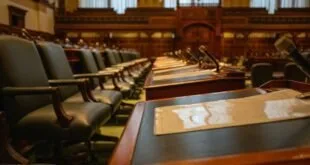 Sala de sessões com mesas de madeira, cadeiras estofadas, microfones, ilustração sobre Oposição avança no Senado