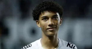 Jovem com cabelo preto encaracolado em camiseta branca, símbolo de Robinho Jr., em close