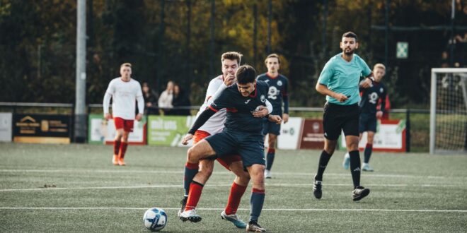 Jogadores em ação durante uma partida de futebol ao ar livre em um campo de grama