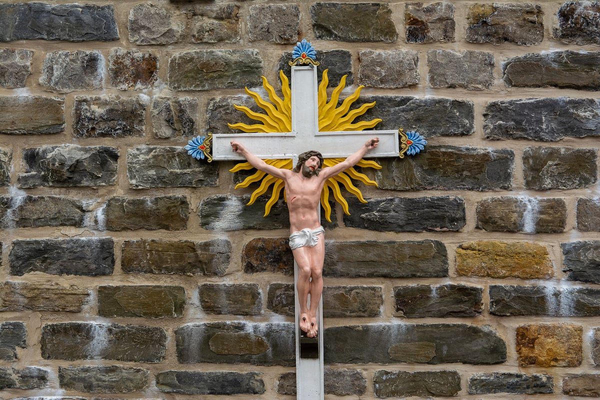 cruz de madeira simples apoiada em parede de pedra antiga