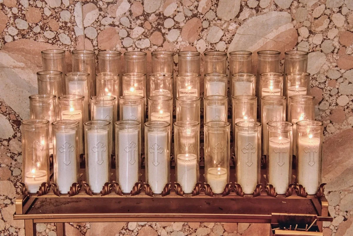 Vela acesa diante de uma imagem de coração cercado por flores em um altar simples