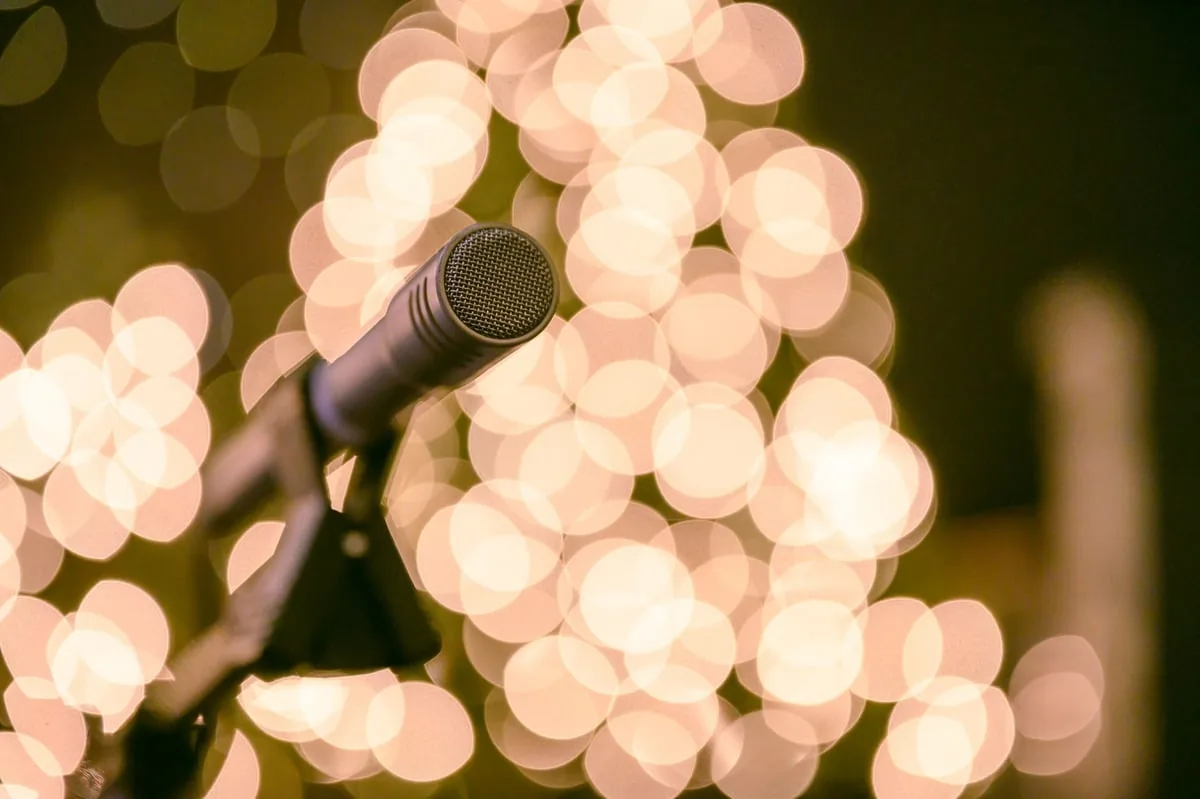 microfone de pé iluminado sobre um palco vazio de teatro